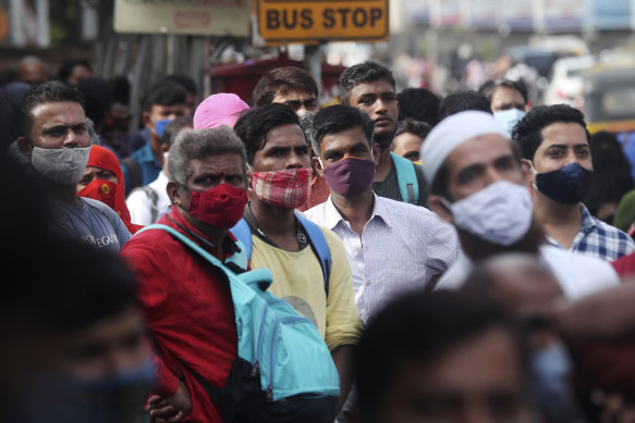 People wait at a bus stop as restrictions ease in Mumbai, India, on Monday.