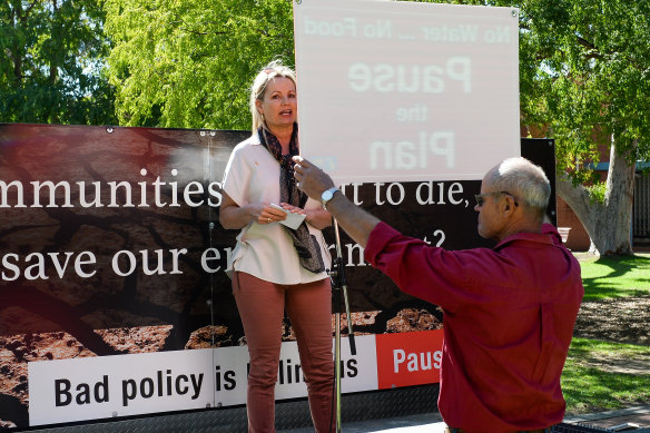 A protester holds a 'Pause the Plan' sign in front of Sussan Ley at a rally in Albury in April.  