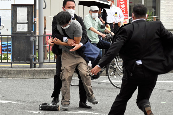 Security police the suspect believed to have shot Shinzo Abe. A homemade gun lies at his feet.