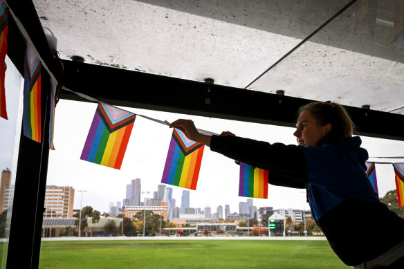 Mugars club president Maddie Sheedy hangs pride flags in the commentary box ahead of their pride round match. 
