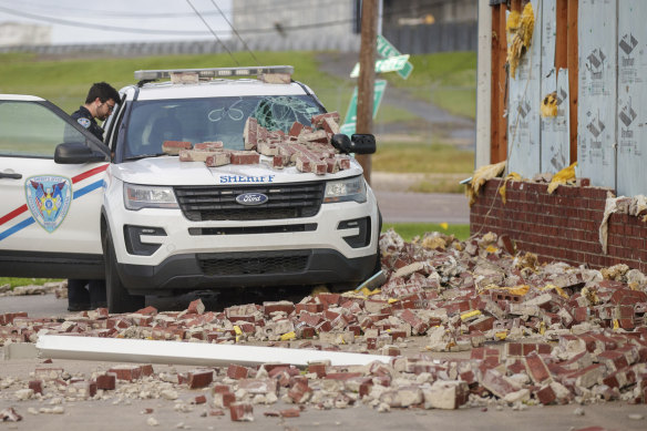 Jefferson Parish deputy Robert Chehardy cleans out his patrol car on Monday after a wall of bricks from the Bridge City Fire Department building collapsed during Hurricane Ida.
