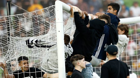 Fans swing on the goal after storming the pitch at AAMI Park on Saturday night.
