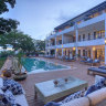 A central dining and lounge area wraps around a chequerboard-bottomed pool.