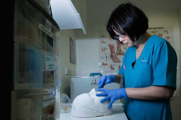 Akane Katsu carving a mask cast from the face of a patient.