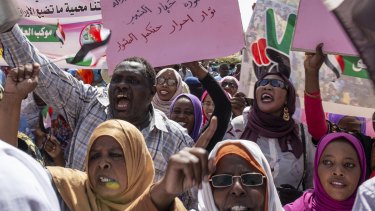 Protesters carry posters in Arabic that say "Freedom, justice, and peace, and the revolution is the choice of the people," at the sit-in outside the military headquarters in Khartoum, Sudan.