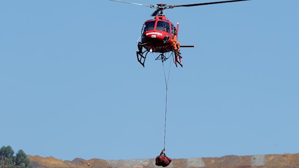 A helicopter lifts a body recovered from the mud five days after the dam's collapse.