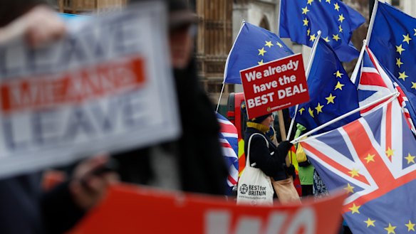 Pro and anti Brexit demonstrators wave their placards and flags outside the Houses of Parliament in London.