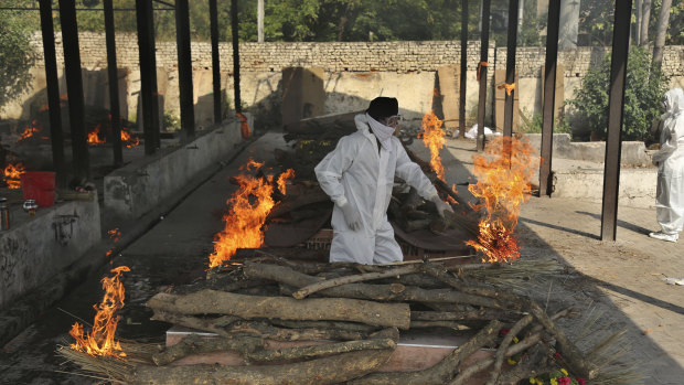 A family member performs the last rites of a COVID-19 victim at a crematorium in Jammu, India, on Friday.