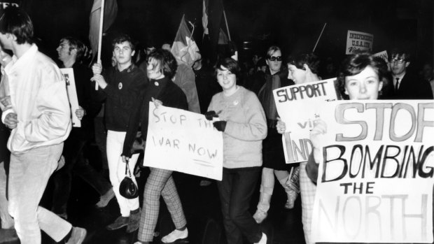 Protesters march by carrying signs and flags.