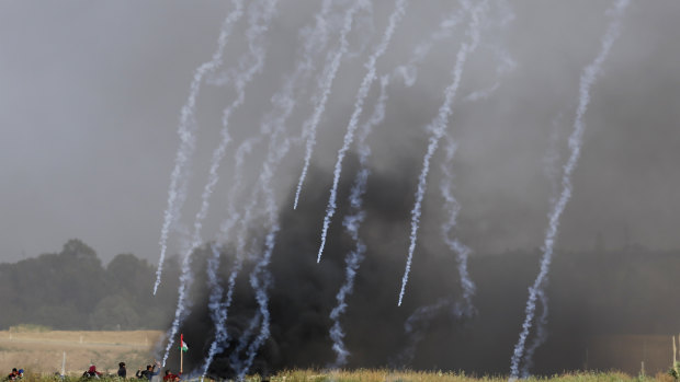 Teargas canisters fired by Israeli troops fall down at Palestinians during the demonstration.