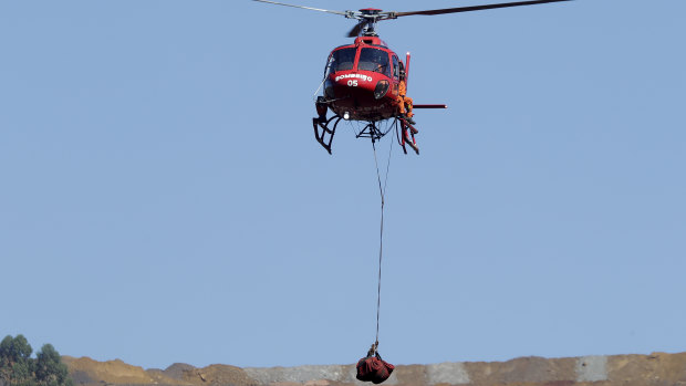 A helicopter lifts a body recovered from the mud five days after the dam's collapse.