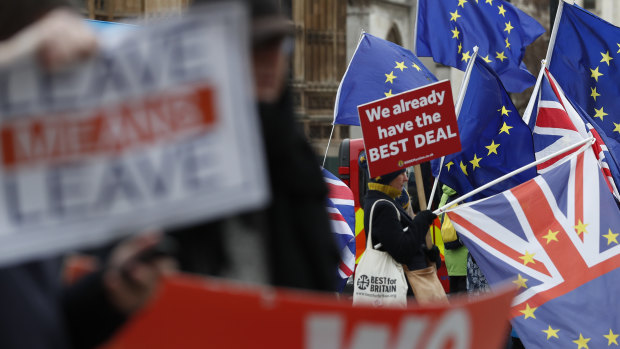 Pro and anti Brexit demonstrators wave their placards and flags outside the Houses of Parliament in London.