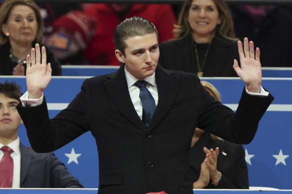 Barron Trump waves at an indoor Presidential Inauguration parade event in Washington.