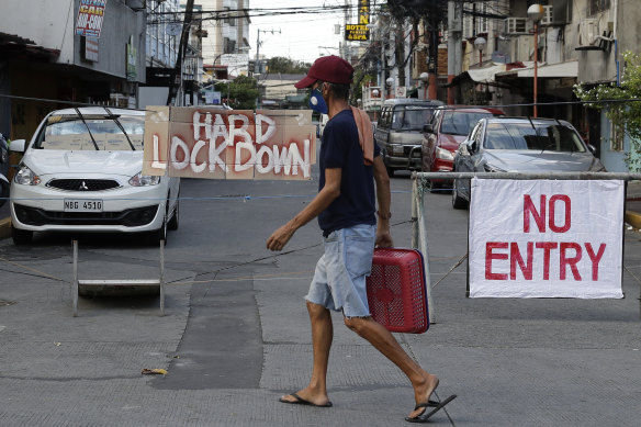 A man passes signs blocking a road during strict community quarantine to prevent the spread of the new coronavirus in Manila.