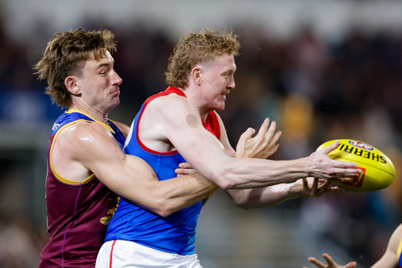 Clayton Oliver of the Demons is tackled by Harris Andrews of the Lions.