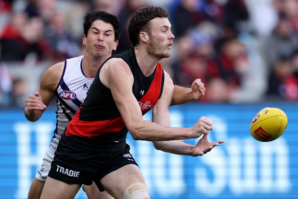 Nik Cox of the Bombers handballs in 2024.