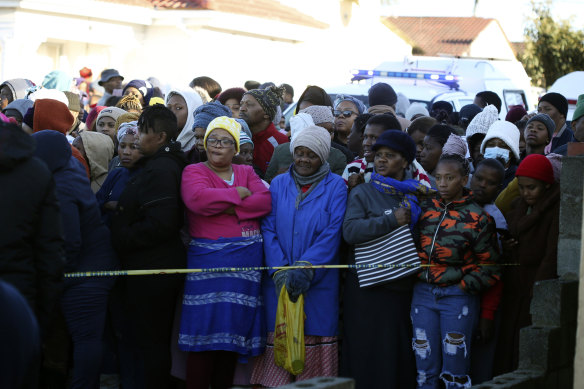 People stand behind a police cordon outside a nightclub in East London, South Africa, on Sunday June 26.