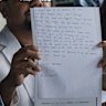 The lawyers for Jazmyn Gourdeas, the wife of slain Melbourne man Zivan Radmanovic, hold up her handwritten note at a press conference in Bali on Tuesday.  