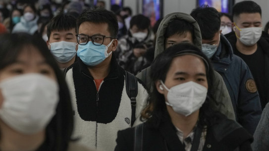 Masked commuters head to work during the morning rush hour in Beijing in December 2022.