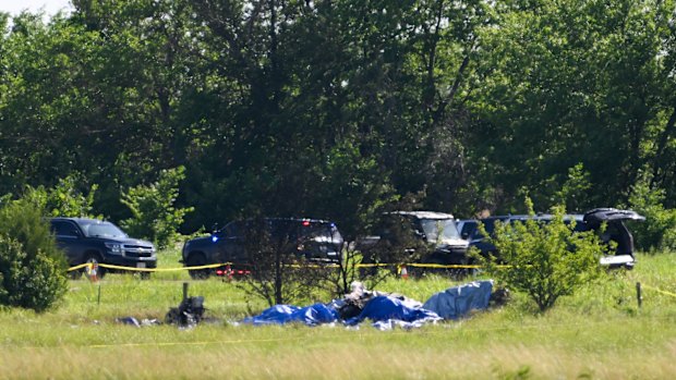 Part of the wreckage of a plane crash is covered with a blue tarp.