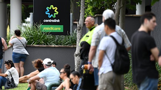 People are seen in long queues outside  Centrelink offices.