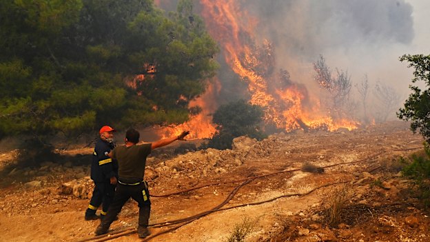 Locals help firefighters as they try to extinguish a wildfire burning near the village Vlyhada near Athens.