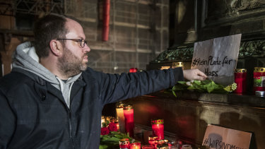 People place candles, flowers and signs against racism at the Brueder Grimm monument after a vigil for the victims near the Midnight shisha bar, one of the sites of the shootings in Hanau, Germany.
