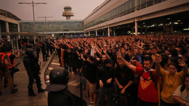 Riot policemen watch protesters outside El Prat airport in Barcelona, Spain.
