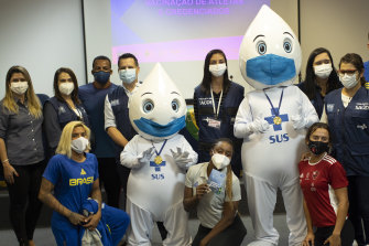 Brazilian athletes, health workers and military officers pose for a photo with COVID-19 vaccination mascot, Joseph Droplet, after the athletes received Pfizershots in Rio ahead of the Tokyo Olympic Games.