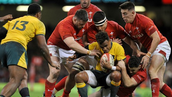 Swamped: Will Genia is tackled by a host of Welsh defenders.
