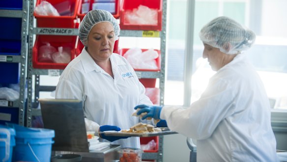 Viki and Kathy prepare and weigh a business class meal inside the cold kitchen.