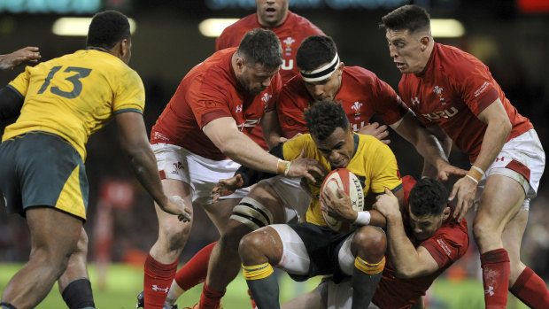 Swamped: Will Genia is tackled by a host of Welsh defenders.