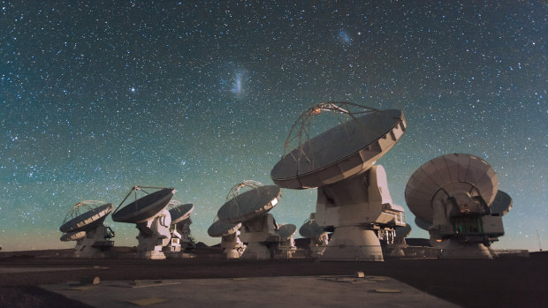 Antennas of the Atacama Large Millimetre/submillimetre Array (ALMA), on the Chajnantor Plateau in the Chilean Andes. The Large and Small Magellanic Clouds, two companion galaxies to our own Milky Way galaxy, can be seen as bright smudges in the night sky, in the centre of the photograph.