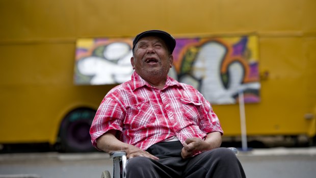 George Thaung, the owner of the Mandalay Bus in Braddon, celebrates the restoration of the bus in 2013.