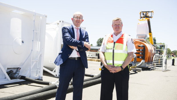 Canberra Airport managing director Stephen Byron and ACT Emergency Services Agency commissioner Dominic Lane stand in front of the the fire retardant filing station at ACT's first fire bombing airbase.