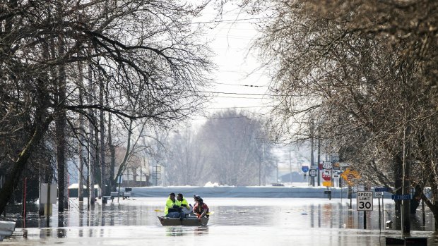People on a boat float down floodwaters that cover Washington Street in Hamburg, Iowa, on Wednesday. 