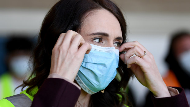 New Zealand Prime Minister Jacinda Ardern adjusts her mask.