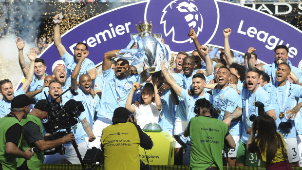 Manchester City players lift the English Premier League trophy after drawing with Huddersfield Town at Etihad Stadium on Sunday.