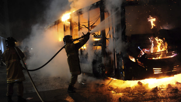 A firefighter extinguishes a burning bus, during a nation-wide education strike in Rio de Janeiro, Brazil.