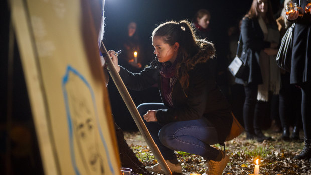 Anna Williams writes a message at the vigil for Eurydice Dixon at Haig Park. 