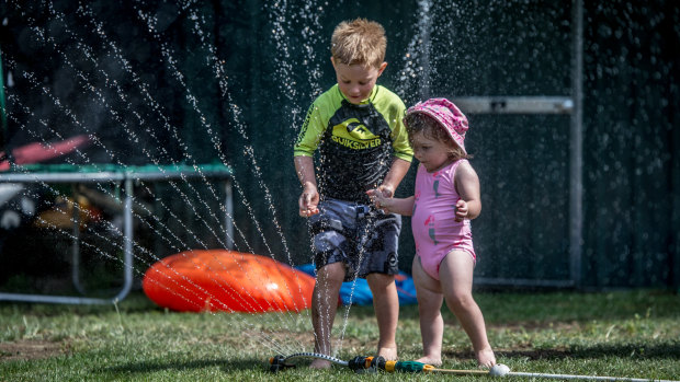 Cooper Bond, 5, and his sister Ivy, 2, of Jerrabomberra play with water in their backyard to cool off during the heatwave.
