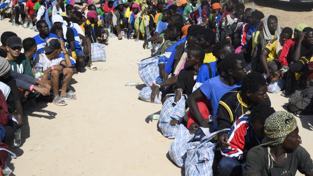 Migrants sit outside the Lampedusa’s migrant reception centre.