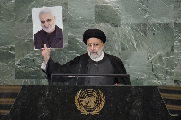 Iranian President Ebrahim Raisi holds a photo of slain general Qassem Soleimani as he addresses the 77th session of the United Nations General Assembly.