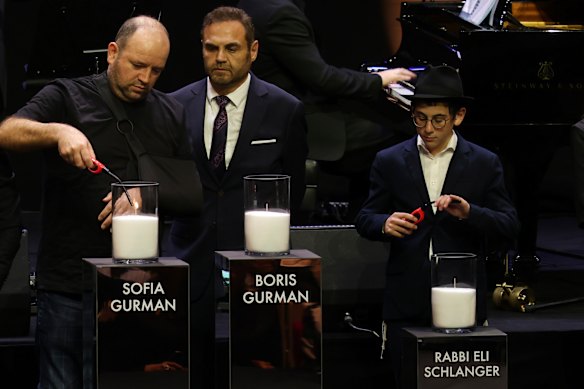 Relatives and Bondi hero Ahmed al Ahmed (left) light candles for each victim at the Opera House.