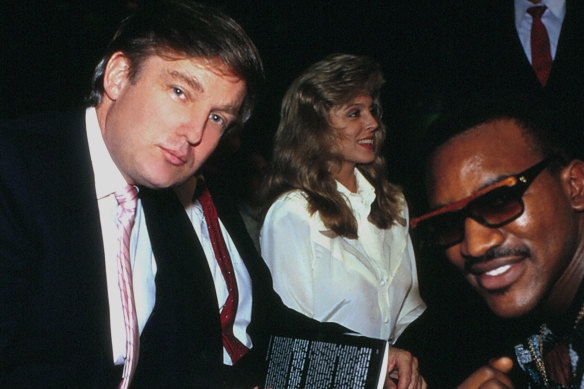 Donald Trump signs a copy of his book for Evander Holyfield in Atlantic City in 1989, as Marla Maples sits beside him.
