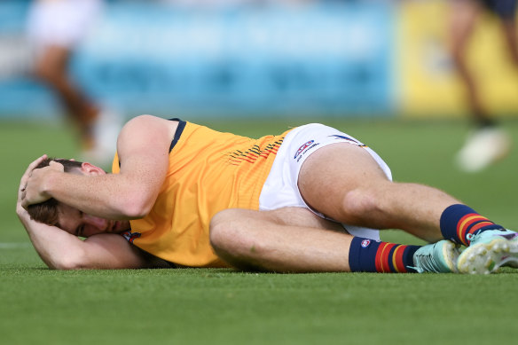 Adelaide’s Mark Keane holds his head after being concussed by Port’s Sam Powell-Pepper.
