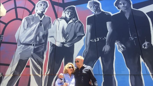 The Saints co-founder Ed Kuepper stands before the mural with Carol Bailey, sister of singer Chris Bailey, who today lives in Holland.