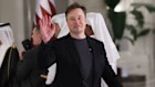 Elon Musk waves as he arrives for a state dinner at the Lusail Palace in Doha, Qatar.