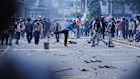 Protesters throw rocks towards riot police during a protest against lavish allowances given to parliament members, in Jakarta.