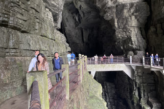 Tourists pass over a bridge above where the Qing River flows through Tenglong Cave.
